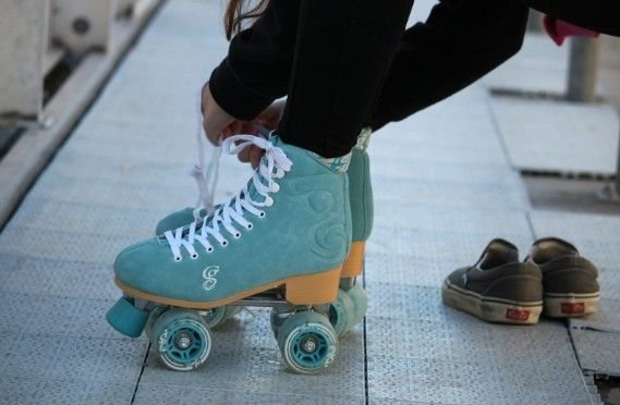Hands tying teal quad roller skates. Does roller skating burn calories Yes, get ready for a calorie-burning ride.